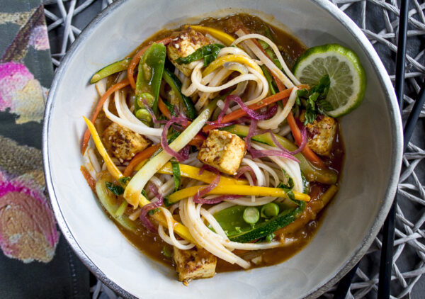 A comforting, warm bowl of flavorful noodles infused with flavors of ginger, garlic, red chiles and coconut milk. A quick basting sauce transforms tofu & chicken into delicious morsels to toss in. A large dose of vegetables makes for a healthful meal.