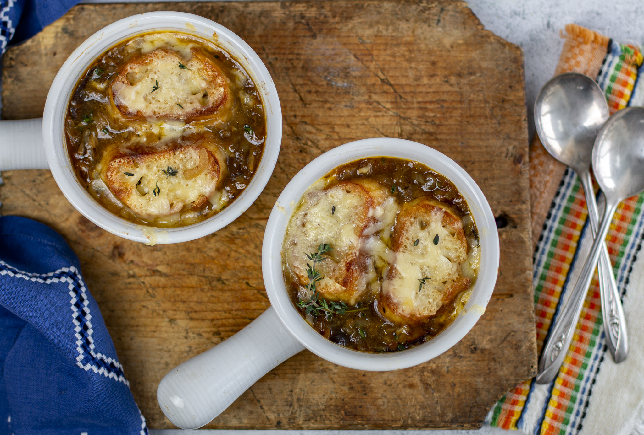 Classic french Onion Soup in white modern crocks on a wooden board with vintage linens