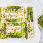 Grilled Asparagus & Hearts of Palm in a quilted pattern with Chimichurri Sauce on a vintage white plate