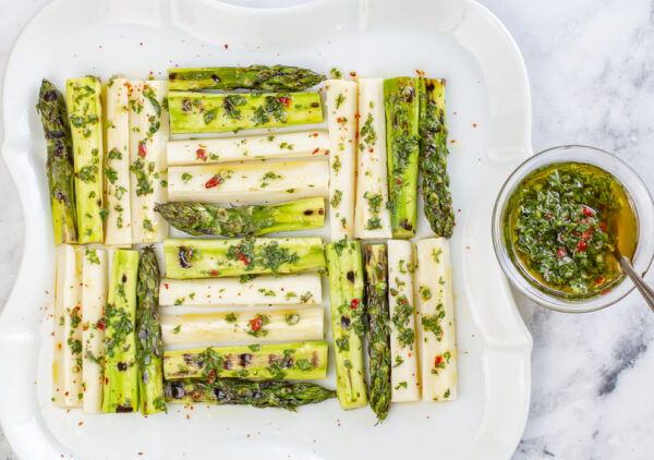 Grilled Asparagus & Hearts of Palm in a quilted pattern with Chimichurri Sauce on a vintage white plate