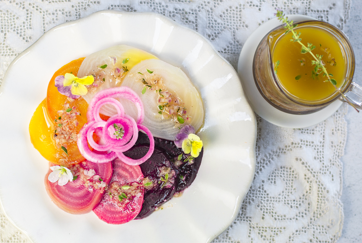 Four different colors of steamed beets with pickled onions and shallot-thyme vinaigrette in a bowl