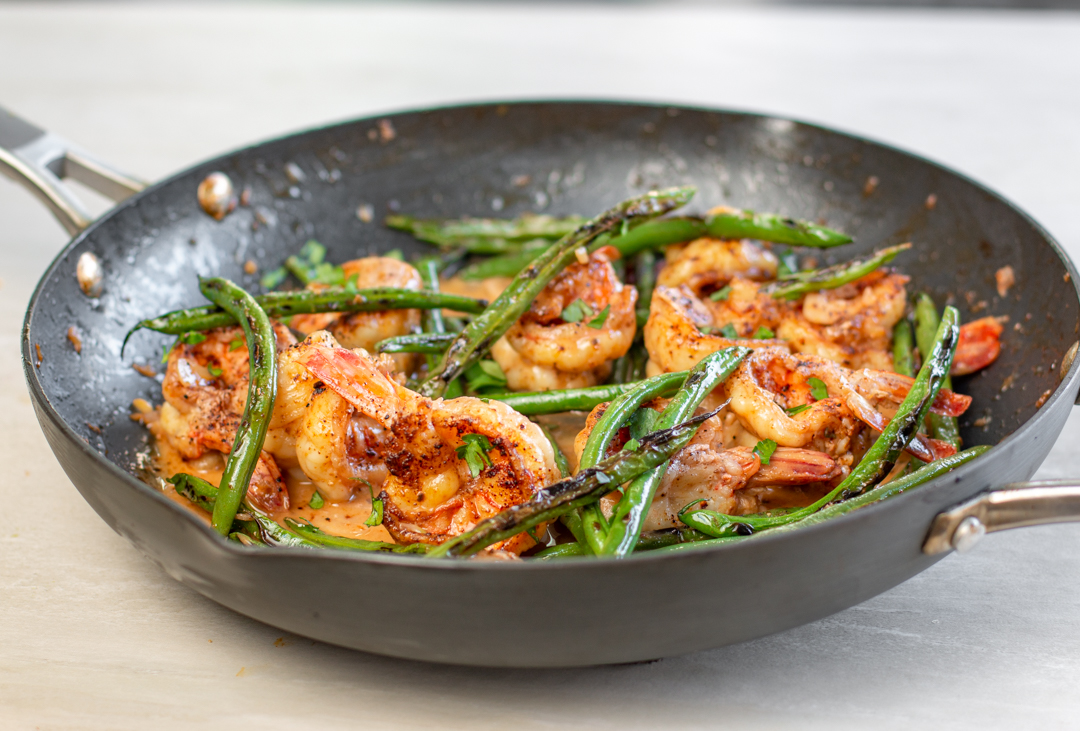 Blackened green beans are added to the pan of shrimp and blood orange sauce