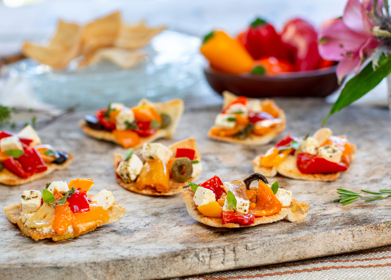 Serving the Mediterranean Slow-Baked Appetizer with Feta, Colorful Peppers, Olives & Garlic on toasted pita triangles