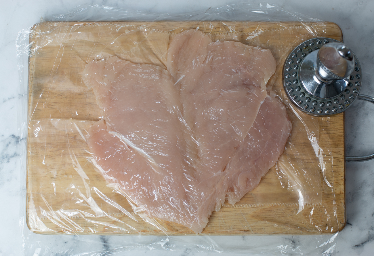 Lay each chicken breast down, cover with plastic wrap and pound thinly and evenly 