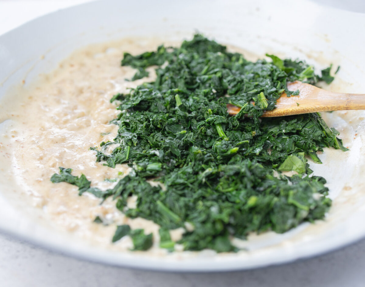 Adding the cooked, chopped spinach to the vegan cream sauce - stir in