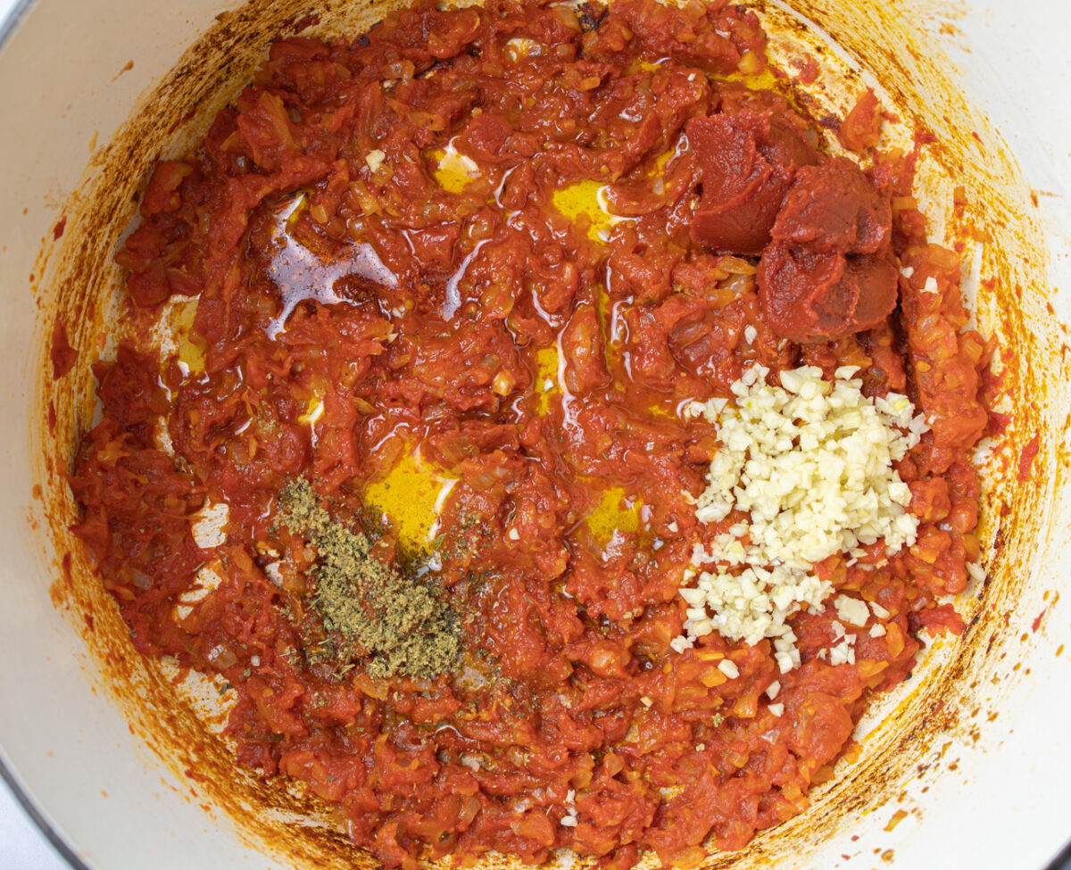 Next - add the flavoring ingredients: remaining tomato puree, tomato paste, garlic (I like lots of it!), dried oregano, chili flakes and evoo